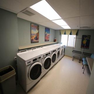 A clean, well-lit laundry room featuring several washing machines along the wall.