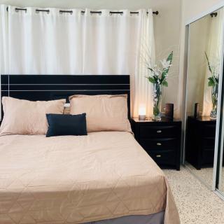 A cozy bedroom with modern and minimalist decor, featuring a neatly made bed, mirrored closet doors, and stylish nightstands.