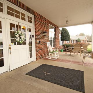 A welcoming porch with a rocking chair, patio furniture, and a wreath on the door.