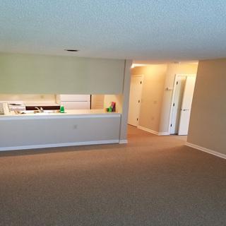 A spacious living room with a view into the kitchen and a long hallway.