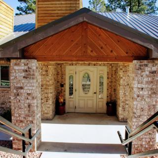 A brick building entrance with a wooden gable and decorative door.