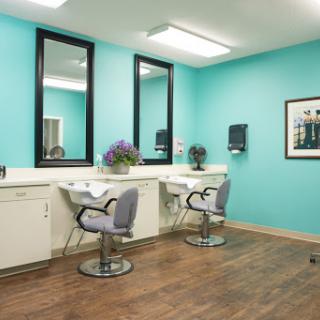 A modern salon interior featuring stylish chairs and large mirrors against a vibrant blue wall.