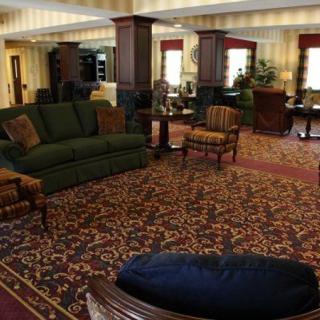 A cozy hotel lobby with elegant furnishings and rich carpeting, featuring sofas and chairs arranged for relaxation.