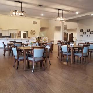 A spacious and well-lit dining area with multiple tables and chairs, featuring wooden flooring and modern decor.