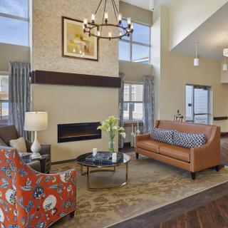 A modern living room featuring a cozy seating arrangement with a sofa and armchair, centered around a fireplace and illuminated by a chandelier.