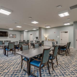 A spacious conference room with multiple tables and chairs arranged for a meeting.