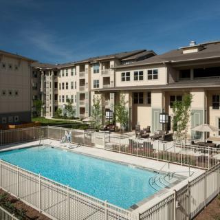 An apartment complex featuring an outdoor swimming pool with surrounding seating.