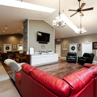 A modern living room with a red sofa, hardwood floors, and elegant chandeliers.