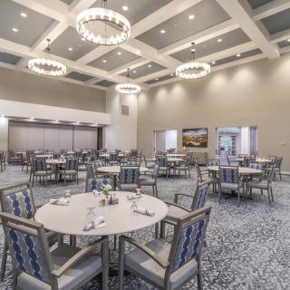 An elegantly designed banquet hall with round tables and chandeliers, ready for an event.