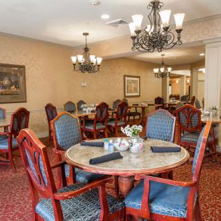 An elegant dining room with upholstered chairs and chandeliers.