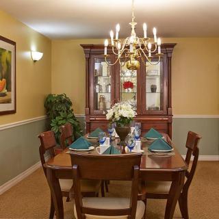 A traditional dining room with a wooden table and chairs, set under an elegant chandelier.