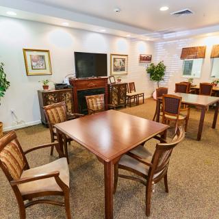 A cozy dining area with tables and chairs set up, featuring a television and decorative elements.