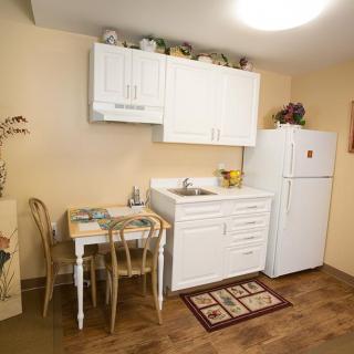 A cozy, compact kitchen with white cabinets, a small dining table, and a refrigerator.