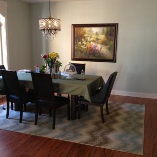 A cozy dining room with a table set for dinner, featuring a chandelier and artwork on the wall.