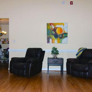A cozy living room setup with two black chairs, a small table with a plant, and abstract artwork on the wall.