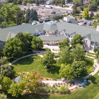 Aerial view of a large building surrounded by lush greenery and landscaped gardens.