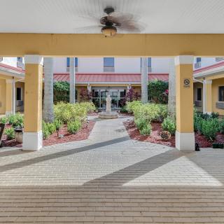 A well-maintained entrance with a landscaped garden and pathway, flanked by columns.