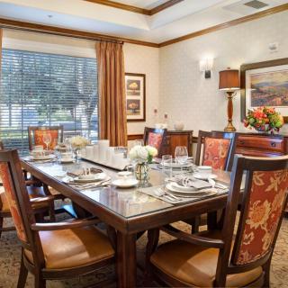 A formal dining room with a large table set for a meal, featuring elegant decor and artwork on the walls.