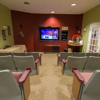 A cozy home theater room with multiple rows of seating and a large screen.