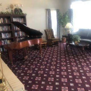A cozy living room with a grand piano, bookshelf, and comfortable seating.