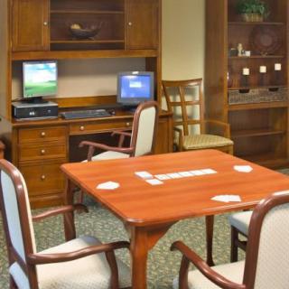 A cozy office space featuring a wooden table, chairs, and two computers on a desk.