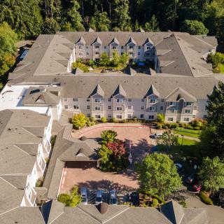 Aerial view of a large residential building surrounded by lush greenery and gardens.