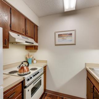 A compact kitchen with wooden cabinets, a stove, and a sink in an apartment.