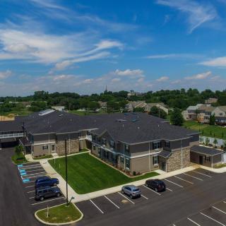 Aerial view of a suburban building with adjacent parking lot under a partly cloudy sky.