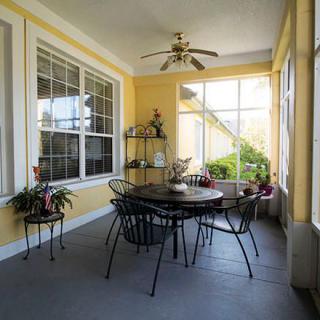 A cozy sunroom with a dining set and potted plants by the windows.