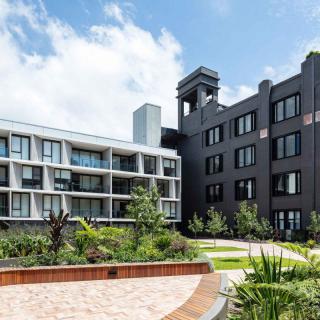A modern apartment complex with well-maintained landscaping in an urban setting.
