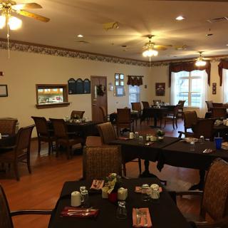 An indoor dining area with arranged tables and chairs, warm lighting, and decorative elements.