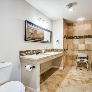 A modern bathroom featuring a double sink, large mirror, and tiled shower area.