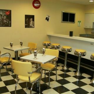 A retro-style diner with checkered flooring, yellow seating, and a classic counter area.