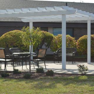 A patio with a white pergola and outdoor seating surrounded by garden landscaping.