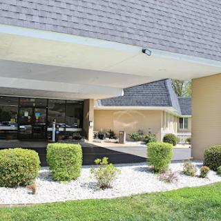 A modern building entrance with landscaped greenery and a surveillance camera.