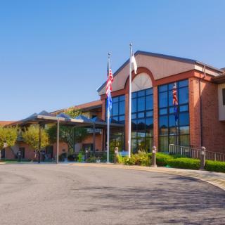 A modern hospital building with flags at the entrance.