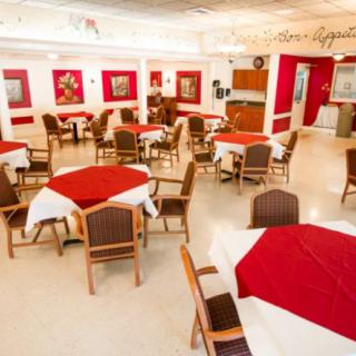 A spacious restaurant dining area with red and white decor, featuring multiple tables and chairs.