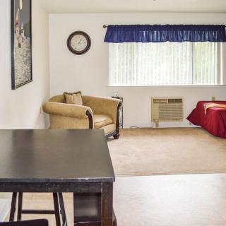 A cozy living room with a chair, table, and a window adorned with blue curtains.