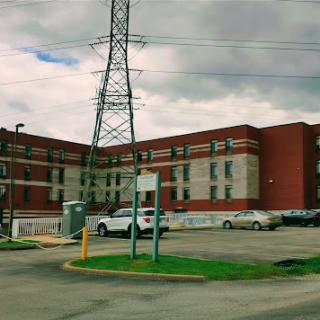 A view of a brick building surrounded by power lines and vehicles in an urban setting.