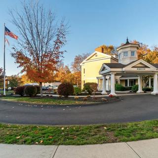 A quaint building with a porch, surrounded by autumn trees and an American flag.