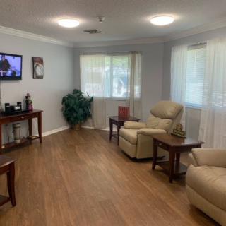 A cozy living room with comfortable seating, a wall-mounted TV, and wooden flooring.