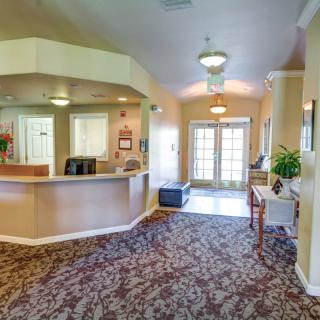 A spacious and well-lit lobby with a carpeted floor, featuring a reception desk and comfortable seating.