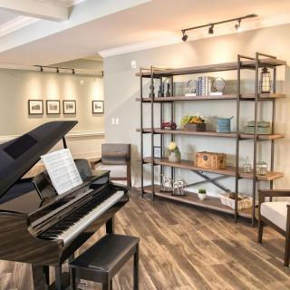 A cozy living room with a grand piano and decorative shelving.
