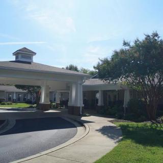 A building entrance with a curved driveway and surrounding trees.