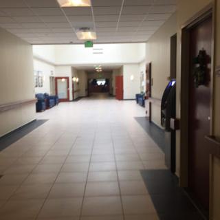 A quiet, empty hallway in a building, featuring tiled flooring and several doors along the sides.