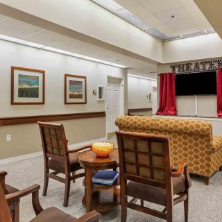 A cozy indoor theater room with seating and a large television, decorated with artwork.