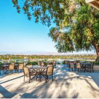 A scenic outdoor patio with tables and chairs under a bright, sunny sky.