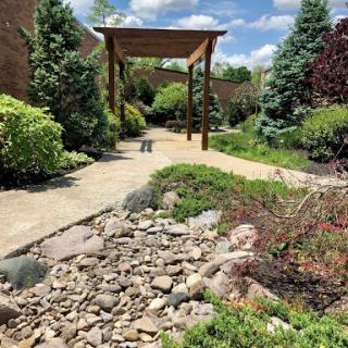 A serene garden pathway surrounded by lush greenery and decorative rocks.