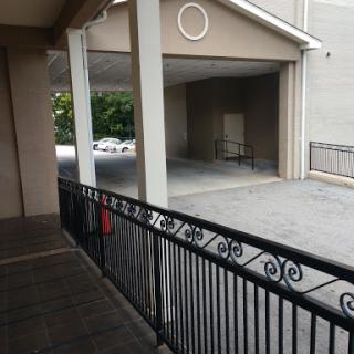 A view of a building's balcony overlooking a parking area.