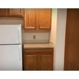 A kitchen area with wooden cabinets and a white refrigerator.